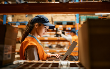 lady in a 3pl warehouse using a laptop
