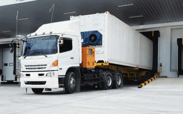 Lorry delivering goods to a warehouse's goods in area.