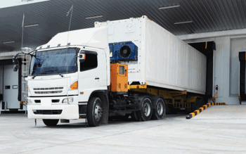 Lorry delivering goods to a warehouse's goods in area.